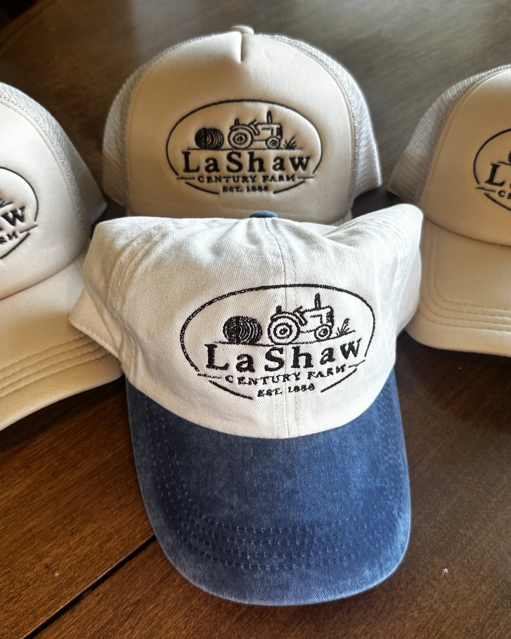Four cream and denim caps embroidered with the LaShaw Century Farm logo