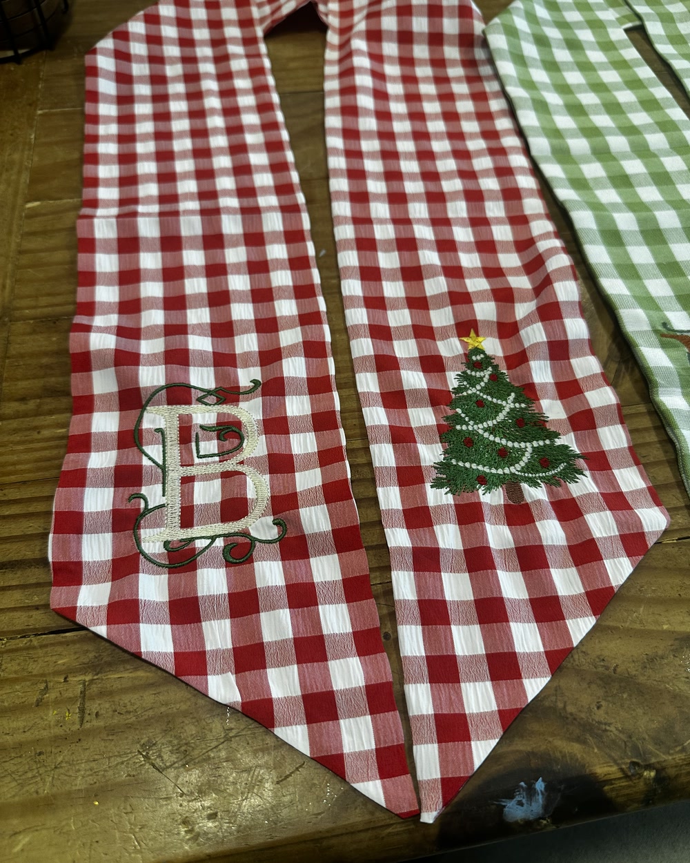 Red gingham table runners embroidered with an ornate letter B and a decorated Christmas tree